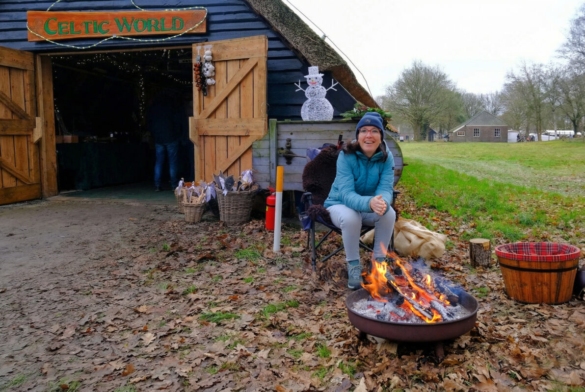 vrouw-zittend-in-stoel-buiten-warmend-bij-vuurkorf