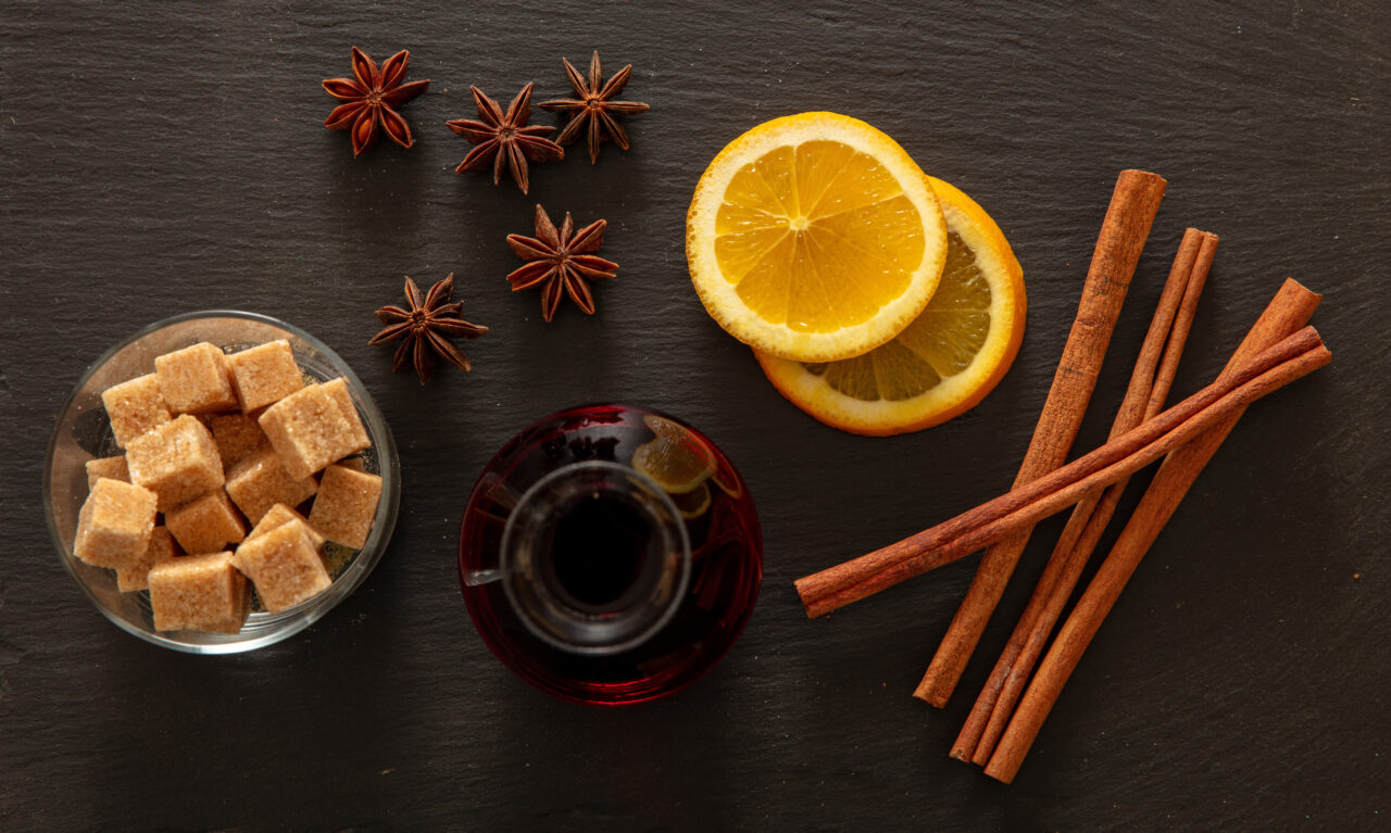 Ingrediënten voor glühwein: sinaasappel, kaneelstokjes, steranijs en suiker — de basis voor een heerlijk verwarmende winterse kerstdrank.